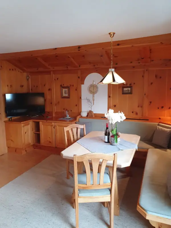 Wohnbereich mit umfangreicher Holzvertäfelung an Wänden und Decke, ausgestattet mit einem modernen Flachbild-TV und einer gemütlichen Sitzecke.