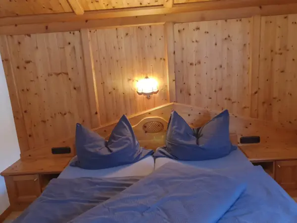 Gemütliches Doppelbett umgeben von hellem Fichtenholz für einen erholsamen Schlaf.
