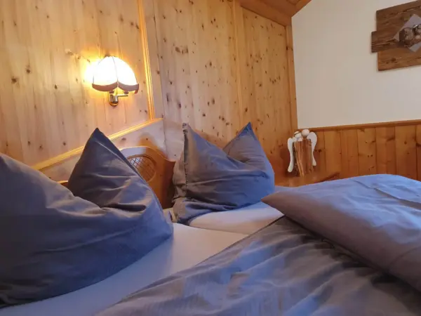 Detailaufnahme im Schlafzimmer: Warme Wandbeleuchtung auf naturbelassener Holzwand.