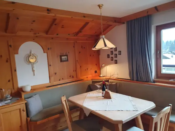 Traditionelle Tiroler Stube mit Holzvertäfelung, großem Esstisch und gemütlicher Beleuchtung.