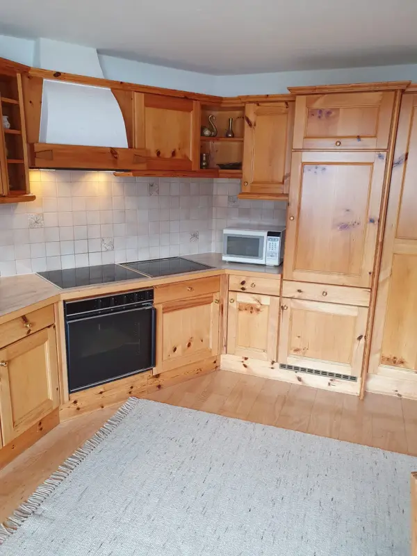 Eckansicht einer voll ausgestatteten Landhausküche aus hellem Holz mit Herd, Backofen und Mikrowelle